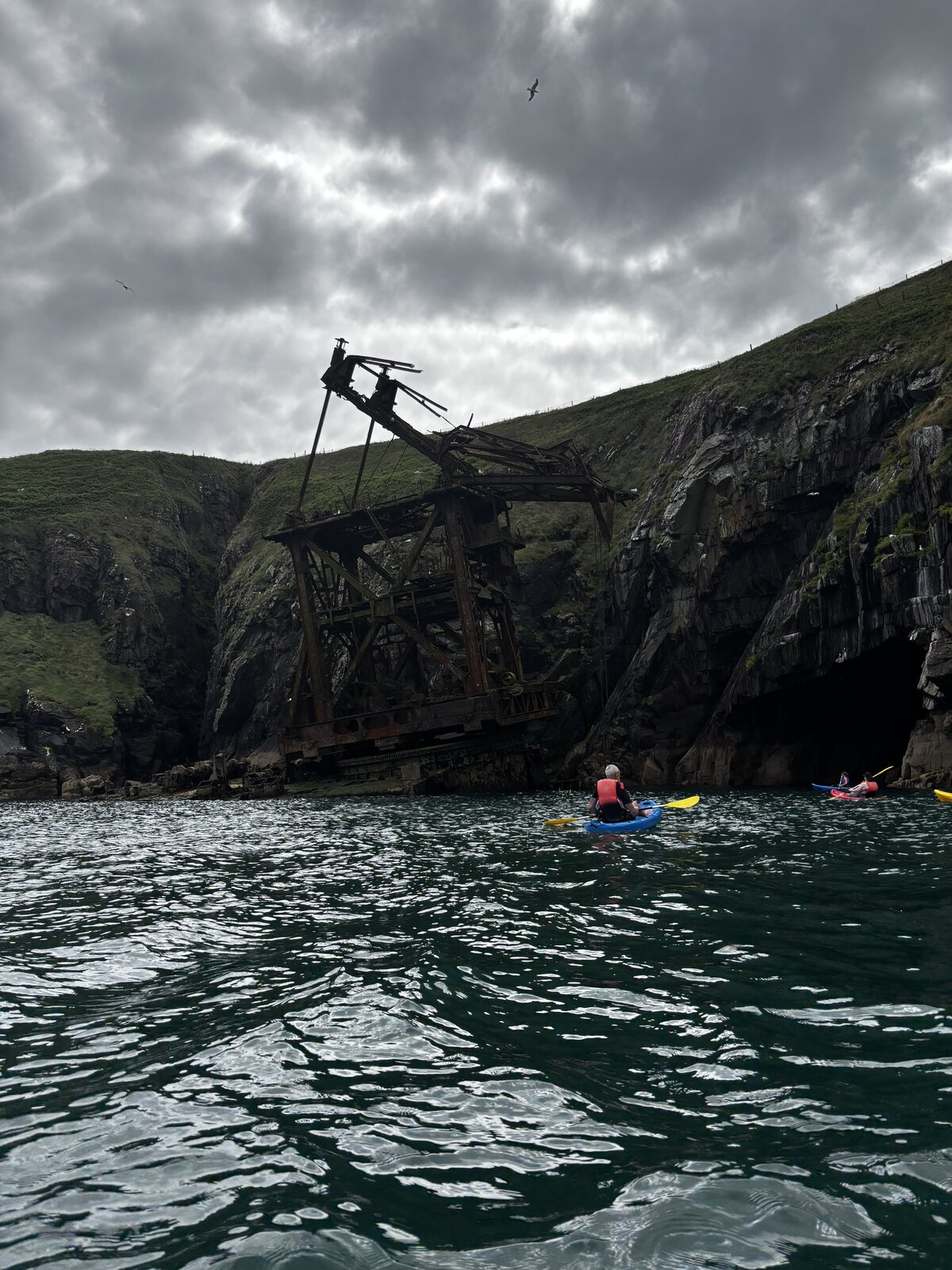 A kayaker beneath the dark cliffs at Ardmore