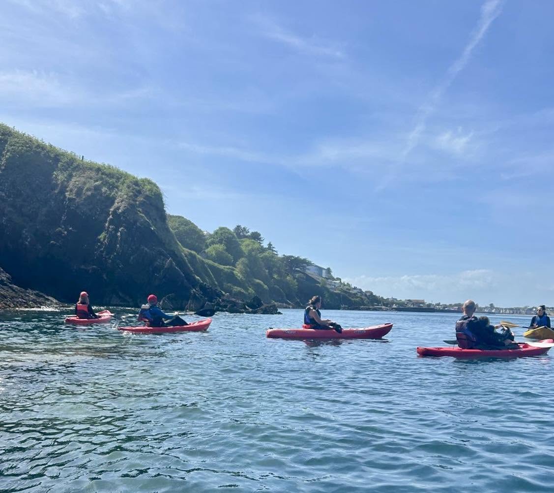 Kayakers paddling beneath the cliffs at Ardmore on the Wild Atlantic Way
